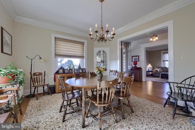 dining space featuring ornamental molding, wood finished floors, baseboards, and a chandelier