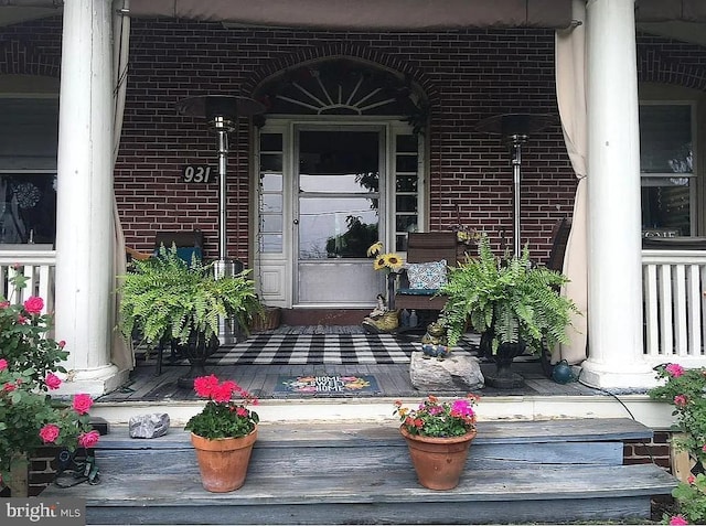 entrance to property featuring brick siding and covered porch