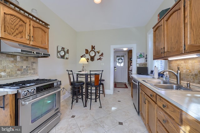 kitchen with baseboards, under cabinet range hood, light countertops, appliances with stainless steel finishes, and a sink