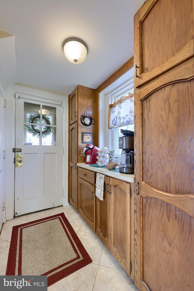 kitchen featuring lofted ceiling, light tile patterned flooring, brown cabinetry, and light countertops