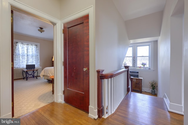 hall with baseboards, radiator, and hardwood / wood-style flooring