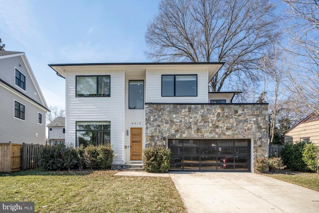 contemporary home featuring stone siding, concrete driveway, a front lawn, and fence