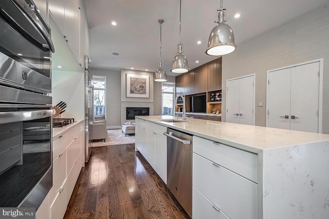 kitchen featuring a large island with sink, a sink, stainless steel appliances, modern cabinets, and open floor plan