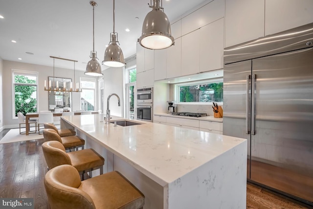 kitchen with a sink, stainless steel appliances, dark wood-type flooring, white cabinetry, and modern cabinets