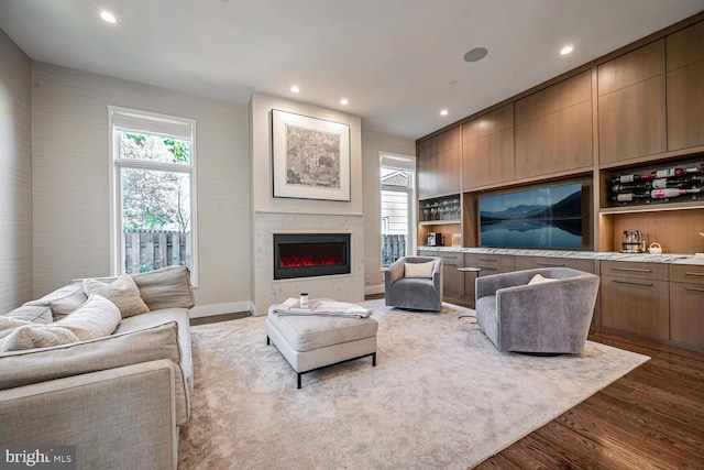 living room featuring recessed lighting, dark wood-style floors, and a lit fireplace