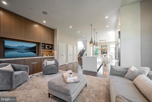 living room featuring a notable chandelier, stairway, recessed lighting, and wood finished floors