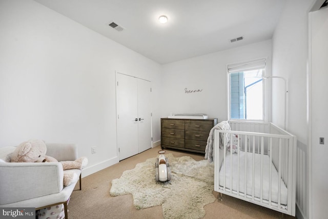 bedroom with a crib, carpet flooring, baseboards, and visible vents