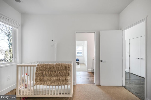 carpeted bedroom with a crib and baseboards