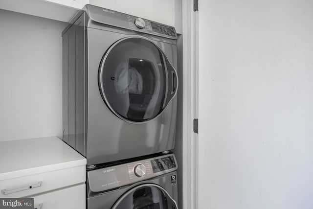 clothes washing area with cabinet space and stacked washing maching and dryer