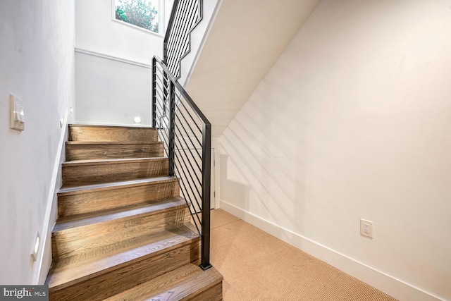 stairway with baseboards and carpet flooring