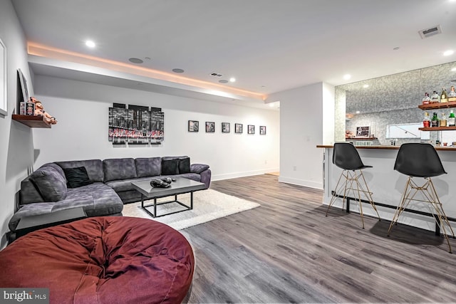 living room with recessed lighting, wood finished floors, baseboards, and indoor bar