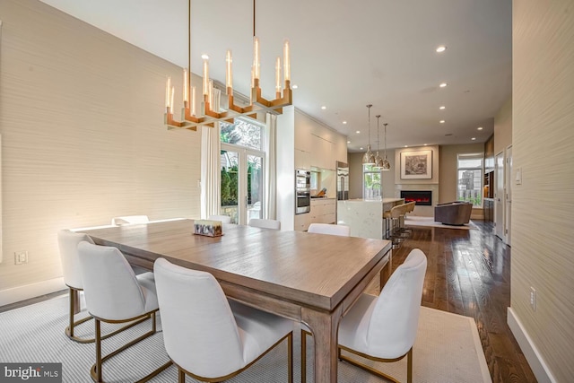 dining area featuring a wealth of natural light, recessed lighting, dark wood-type flooring, and a lit fireplace