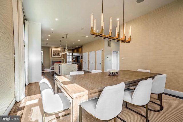 dining area featuring visible vents, a chandelier, dark wood finished floors, recessed lighting, and a warm lit fireplace