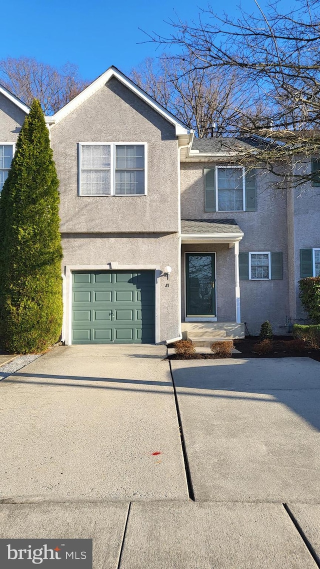 traditional-style home with stucco siding, an attached garage, and concrete driveway