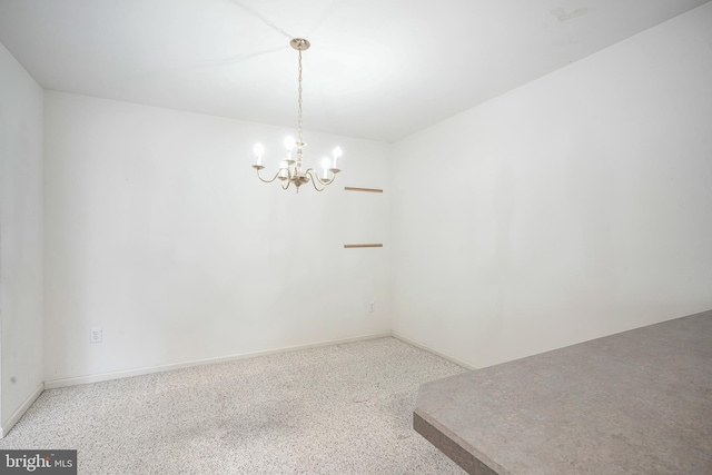 empty room featuring a notable chandelier and baseboards