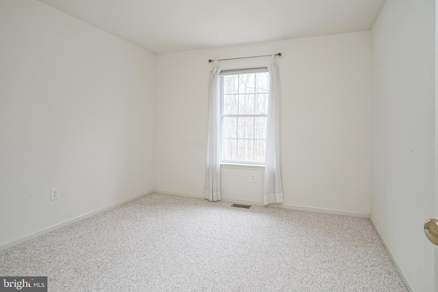 carpeted spare room featuring visible vents and baseboards