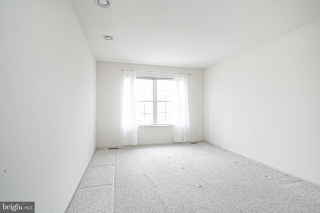 spare room featuring carpet flooring, baseboards, and visible vents