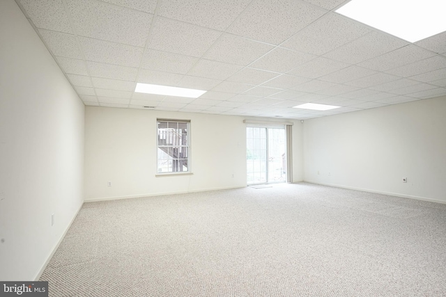 unfurnished room featuring a drop ceiling, baseboards, and carpet flooring