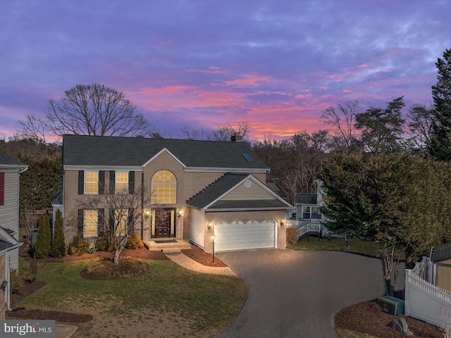 traditional home featuring a garage, fence, aphalt driveway, and a front yard