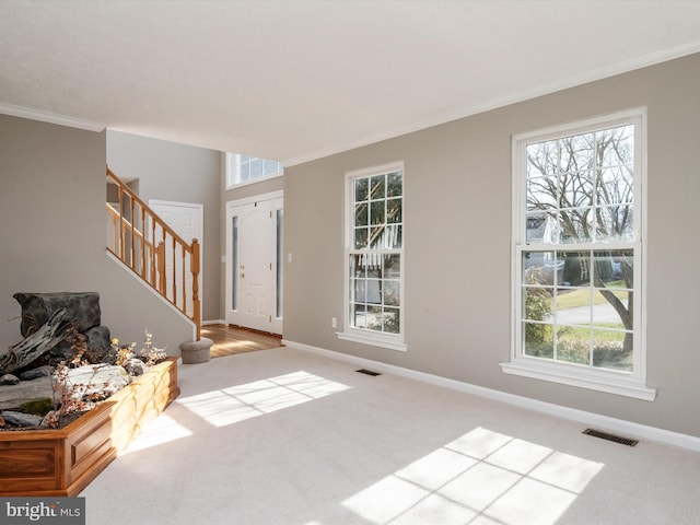 carpeted entryway with stairway, baseboards, visible vents, and ornamental molding