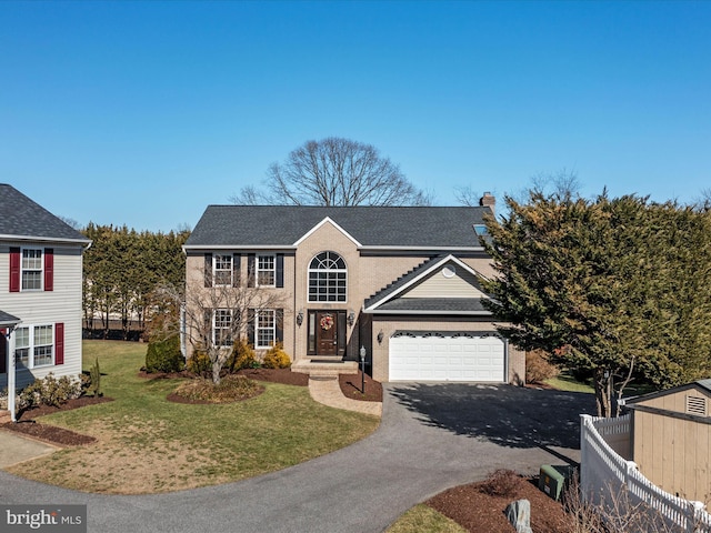 view of front facade featuring a garage, a chimney, aphalt driveway, fence, and a front yard