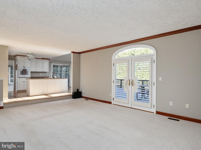 unfurnished living room featuring visible vents, ornamental molding, and light colored carpet