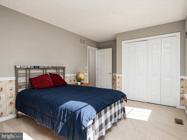 bedroom featuring a closet, visible vents, and light colored carpet