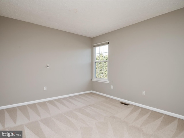 unfurnished room featuring visible vents, light carpet, baseboards, and a textured ceiling