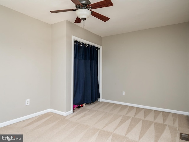 empty room featuring baseboards, visible vents, a ceiling fan, and light colored carpet