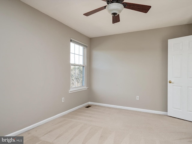 unfurnished room with a ceiling fan, light colored carpet, visible vents, and baseboards