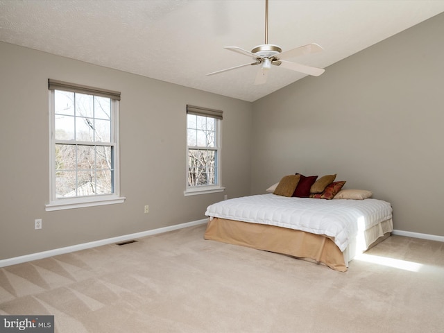 bedroom with light colored carpet, visible vents, vaulted ceiling, a textured ceiling, and baseboards