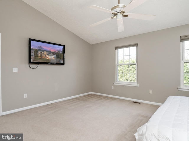 unfurnished bedroom featuring lofted ceiling, carpet floors, multiple windows, and visible vents