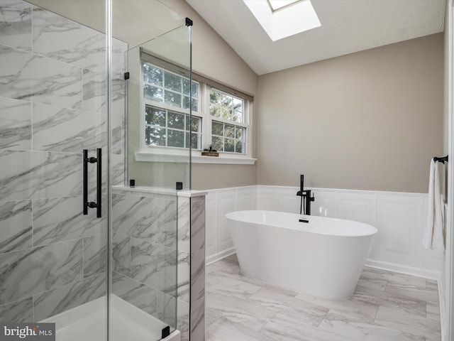 full bathroom with lofted ceiling with skylight, a stall shower, marble finish floor, and wainscoting