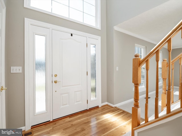 entryway featuring crown molding, visible vents, stairway, wood finished floors, and baseboards