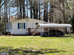 view of front of property featuring a carport and a lawn