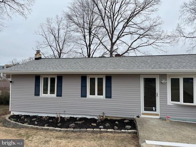 view of front of house with a chimney and roof with shingles