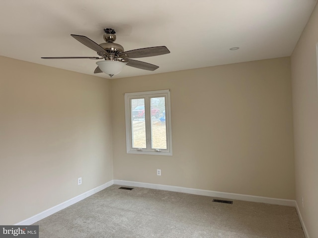 carpeted spare room with visible vents, baseboards, and a ceiling fan