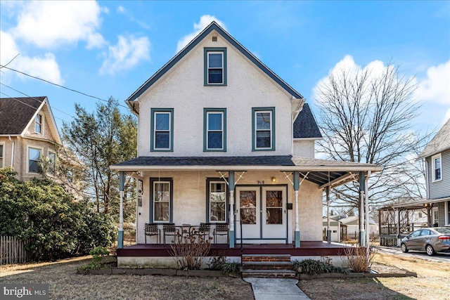 view of front of house featuring roof with shingles, a porch, and stucco siding