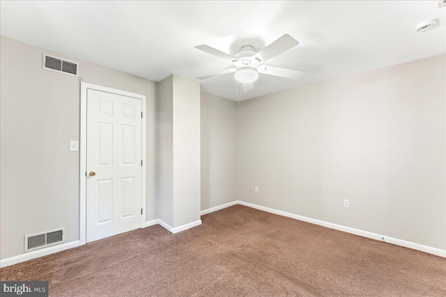 carpeted empty room featuring ceiling fan, visible vents, and baseboards