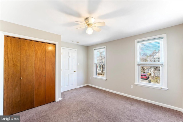 unfurnished bedroom featuring carpet floors, a closet, baseboards, and a ceiling fan