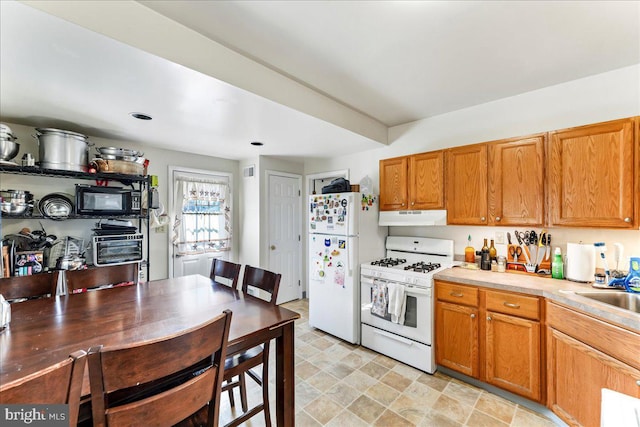 kitchen featuring light countertops, white appliances, brown cabinets, and under cabinet range hood