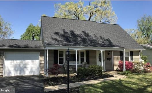 cape cod-style house with a garage, covered porch, and aphalt driveway