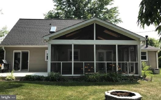 rear view of house with cooling unit, a lawn, a fire pit, and a patio