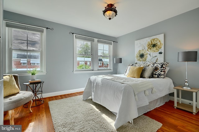 bedroom featuring multiple windows, wood finished floors, and baseboards