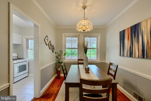 dining room featuring a chandelier, crown molding, baseboards, and light wood-style floors