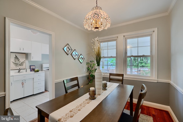 dining space with a chandelier, crown molding, washer / clothes dryer, baseboards, and light wood finished floors
