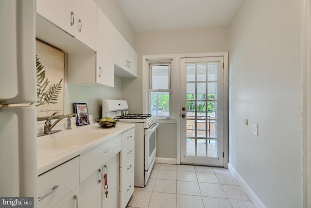 kitchen with white appliances, baseboards, a sink, and light tile patterned floors