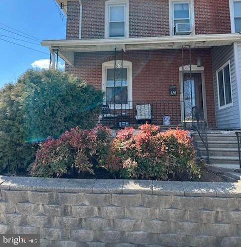 view of exterior entry featuring covered porch and brick siding