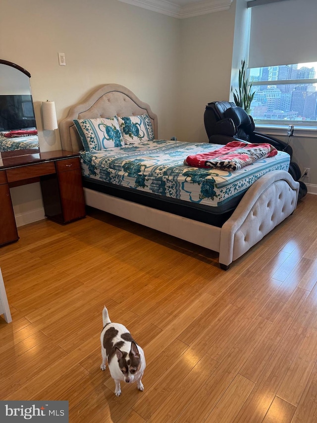 bedroom featuring light wood finished floors, baseboards, and crown molding