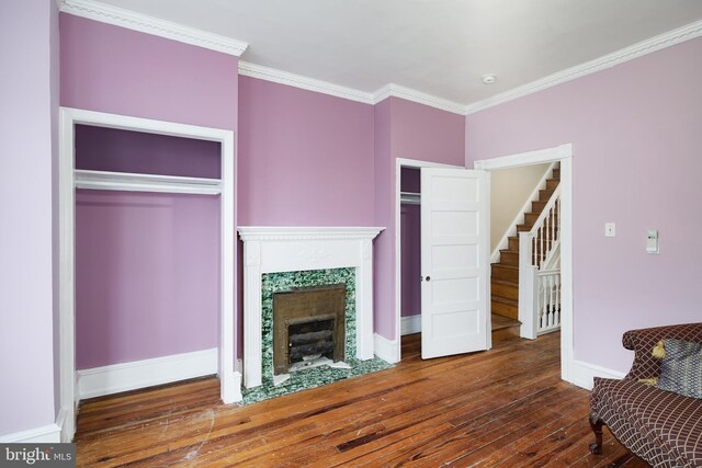 living room featuring stairway, ornamental molding, baseboards, hardwood / wood-style flooring, and a tiled fireplace